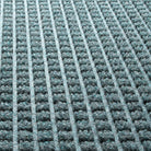 A close-up detailed shot of WaterHog  Square's eco-friendly PET surface, made of light blue, grey, white, and some green polyester fibers.