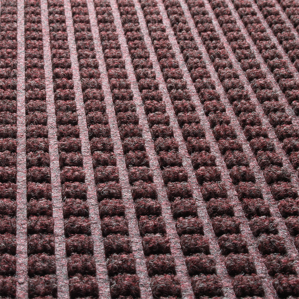 Close-up of WaterHog square's surface recycled eco-friendly fibers made of deep wine reds, whites, and greys, pressed to make a classic design.