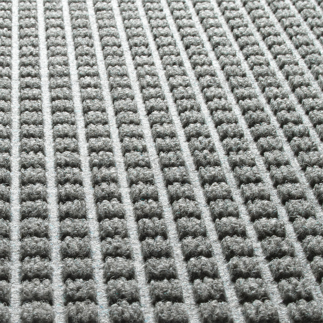 Close-up of WaterHog squares mat fade-resistant recycled PET surface on a light grey, long-lasting doormat with rubber backing.