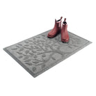 A pair of pink boots sitting on top of a WaterHog Tree of Life outdoor doormat, placed on the far right, top corner, with over half of the mat still left for dirt trapping and water hoggin'.