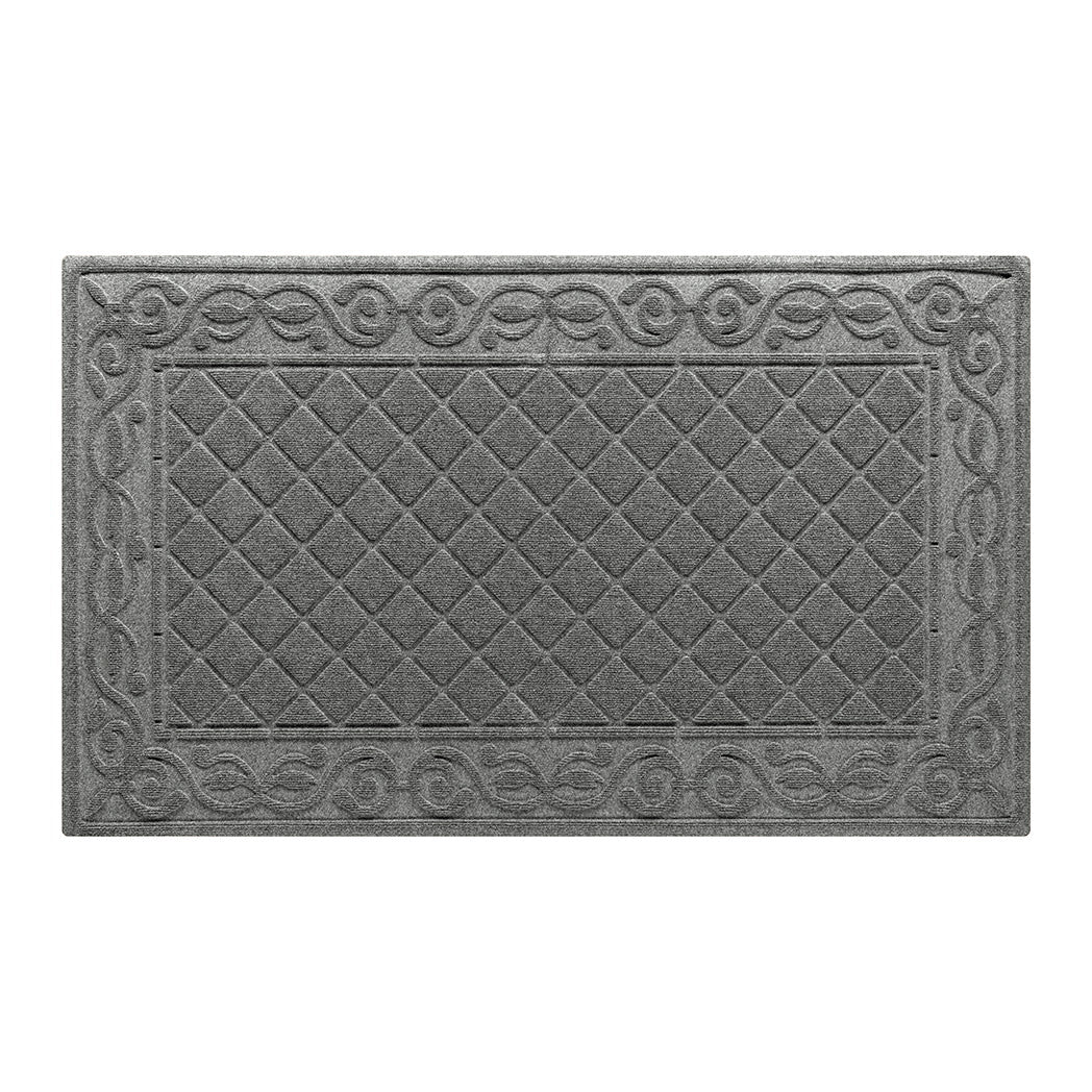 An overhead of a large WaterHog Tristan indoor/outdoor doormat in a soft, neutral grey that features the diamond pattern with an ornate scroll border, shown on a white background.