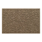 A medium WaterHog doormat in a warm camel color featuring a raised tropical leaf pattern designed to trap dirt and moisture while the bordered edges provide a clean, finished look.