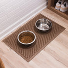 A camel-colored Waves pet bowl mat in an hallway or mud room with a small pet water bowl and pet food dish on top.